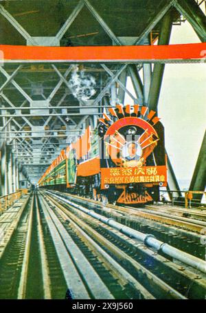 Un'immagine da cartolina in formato A5 del primo treno che attraversa il ponte inferiore della strada a doppio ponte e il ponte ferroviario sul fiume Yangtze a Nanchino in Cina a partire dal 1971 circa. Il titolo sul retro della carta è "il primo treno che attraversa il ponte sul fiume Nanchino Yantse". L'artista/fotografo è senza nome e non vi è alcuna menzione di copyright. Foto Stock