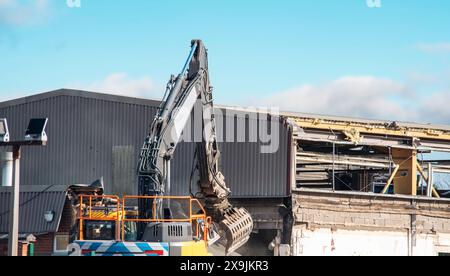 Demolizione di un edificio di oidi per liberare spazio per lo sviluppo di nuove abitazioni a prezzi accessibili. L'escavatore rompe la vecchia casa. Fare spazio per la costruzione di un Foto Stock