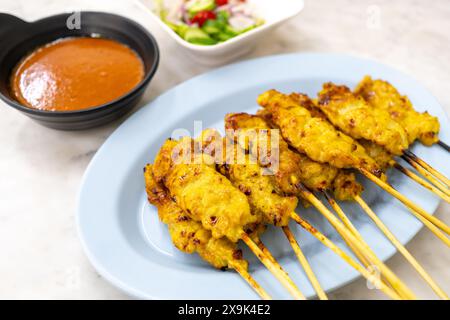 Satay di maiale o maiale alla griglia servito con salsa di arachidi o salsa agrodolce - cucina tailandese in stile asiatico su sfondo bianco. Foto Stock