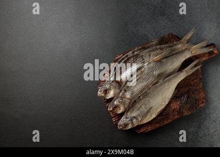 Pesce d'orata essiccato su un tagliere su sfondo nero Foto Stock