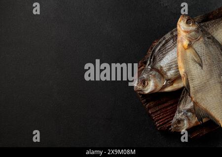 Pesce d'orata essiccato su un tagliere su sfondo nero Foto Stock