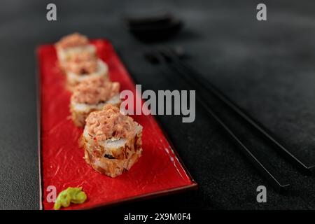 Cibo giapponese: sushi, involtino Shiitaki con tonno, avocado, Philadelphia, kimchi, fiocchi di tonno sfondo nero Foto Stock