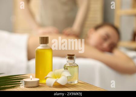 Aromaterapia. Donna che riceve un massaggio alla schiena nel salone spa, si concentra su bottiglie di oli essenziali e candele accese Foto Stock