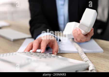 Il Segretario chiama il numero al telefono al tavolo in ufficio, primo piano Foto Stock