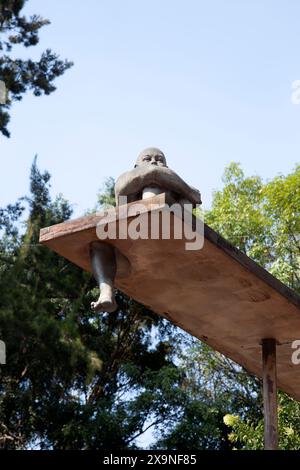 Statua sopraelevata dell'uomo seduto sulla filiale in Avenida Álvaro Obregón nel quartiere Roma Norte di città del Messico, Messico Foto Stock