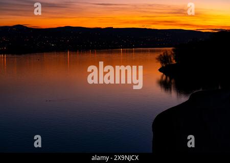 Lo splendido tramonto illumina il fiume Danubio a Novi Sad, Serbia, con vivaci sfumature di arancione e blu, che si riflettono pacificamente sulle acque calme Foto Stock