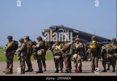 I paracadutisti con tettuccio rotondo si preparano a caricare sull'aereo Douglas C47, noto come Dakota, che divenne il velivolo da trasporto più conosciuto al mondo e vide un uso diffuso da parte degli Alleati durante la seconda guerra mondiale durante l'IWM Duxford Air Show nel Cambridgeshire, mentre attraversavano il Canale per continuare le commemorazioni per il 80 ° anniversario del D-Day. Data foto: Domenica 2 giugno 2024. Foto Stock