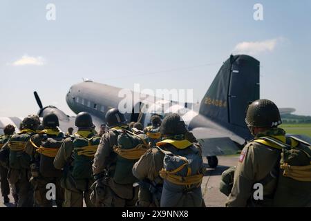 I paracadutisti con tettuccio rotondo si preparano a caricare sull'aereo Douglas C47, noto come Dakota, che divenne il velivolo da trasporto più conosciuto al mondo e vide un uso diffuso da parte degli Alleati durante la seconda guerra mondiale durante l'IWM Duxford Air Show nel Cambridgeshire, mentre attraversavano il Canale per continuare le commemorazioni per il 80 ° anniversario del D-Day. Data foto: Domenica 2 giugno 2024. Foto Stock