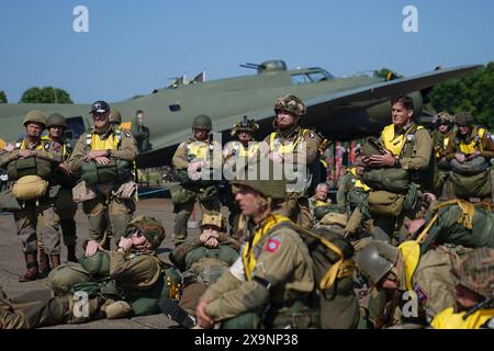 I paracadutisti con tettuccio rotondo si preparano a caricare sull'aereo Douglas C47, noto come Dakota, che divenne il velivolo da trasporto più conosciuto al mondo e vide un uso diffuso da parte degli Alleati durante la seconda guerra mondiale durante l'IWM Duxford Air Show nel Cambridgeshire, mentre attraversavano il Canale per continuare le commemorazioni per il 80 ° anniversario del D-Day. Data foto: Domenica 2 giugno 2024. Foto Stock