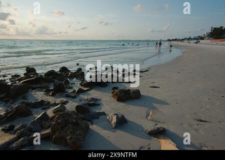 Ampia vista della spiaggia Pass-a-Grille di St. Pete Beach, Florida, guardando a nord. Rocce e molte persone camminano nella sabbia e nell'acqua, vicino al set Foto Stock
