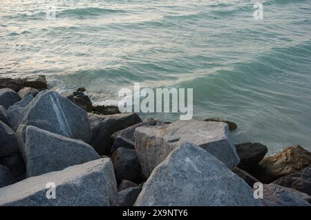 Vista media delle grandi rocce sul bordo della costa vicino al tramonto in Florida. Più colori e onde che si infrangono a circa 45 gradi. Tendina parasole Foto Stock