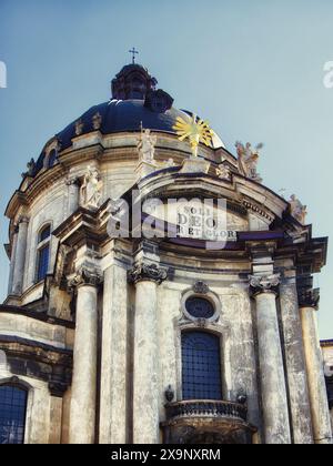 Eleganza barocca: Una facciata di chiesa con testo latino e un sole, sotto un cielo limpido. La chiesa domenicana e il monastero Foto Stock