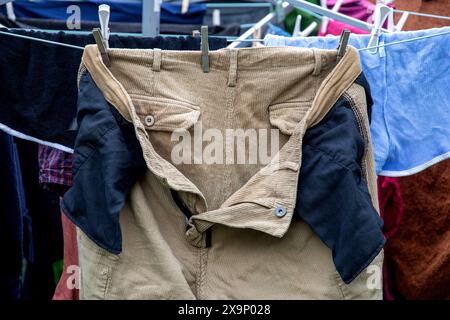 Pantaloni in velluto vellutato all'esterno che si asciugano su una linea di lavaggio del giardino dopo essere stati lavati Foto Stock