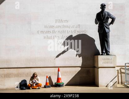 Londra, Regno Unito. 2 giugno 2024. Una donna si rilassa al sole sotto un'ombra gettata dalla statua di George Orwell. La statua di George Orwell dello scultore britannico Martin Jennings è stata inaugurata il 7 novembre 2017 fuori dalla Broadcasting House, la sede della BBC, a Londra. Il muro dietro la statua è inciso con le parole di George Orwell se la libertà significa qualcosa, significa il diritto di dire alla gente ciò che non vuole sentire. Questa era una citazione di una prefazione inutilizzata a Animal Farm. Crediti: Mark Thomas/Alamy Live News Foto Stock