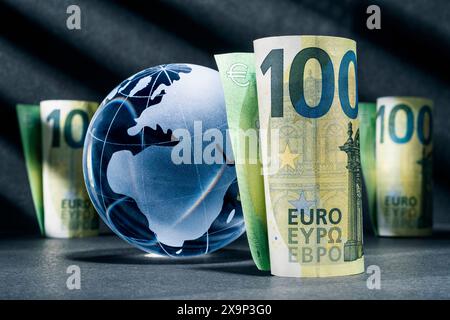 Globo blu con cento banconote in euro su sfondo scuro Foto Stock