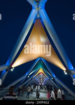 Ponte moderno illuminato con persone che camminano al crepuscolo, mostrando la bellezza architettonica Foto Stock