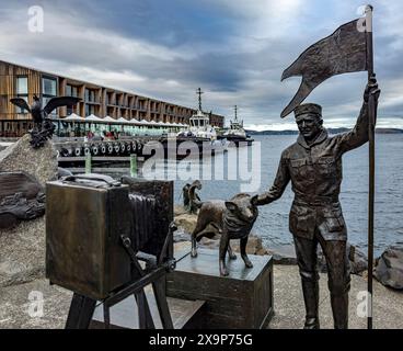 Rappresentazione artistica di una statua di bronzo raffigurante un marinaio e il suo leale cane in riva al mare Foto Stock