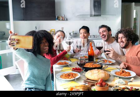 Gruppo di amici che fanno selfie durante il pranzo al chiuso Foto Stock