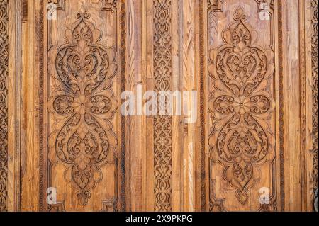 Tradizionali motivi orientali islamici uzbeki ornamenti arabeschi su una vecchia porta in legno intagliata in Uzbekistan da vicino Foto Stock