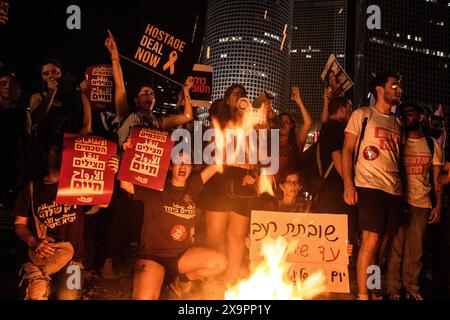 Israele. 1 giugno 2024. I manifestanti cantano intorno a un falò mentre tengono dei cartelli che recitano: “Accordo con gli ostaggi ora”, “accordi salvano vite”, “siamo tutti ostaggi” e “attaccante della fame, giorno 28”. Oltre 100.000 israeliani hanno manifestato con le famiglie degli ostaggi contro il primo ministro Benjamin Netanyahu a Tel Aviv, chiedendo un accordo di ostaggi immidiati e elezioni generali dopo il discorso di Biden. Gli scontri con la polizia israeliana si sono verificati una volta che i manifestanti hanno innescato falò sulla giunzione di Kaplan. Tel Aviv, Israele. 1° giugno 2024. (Matan Golan/Sipa USA). Crediti: SIPA USA/Alamy Live News Foto Stock