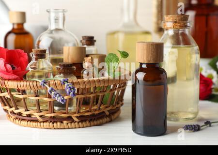 Aromaterapia. Diversi oli essenziali e fiori su tavola di legno bianco Foto Stock