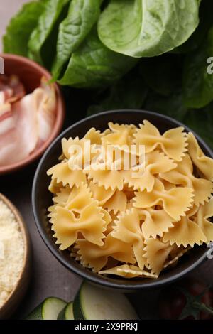 Pasta cruda, pancetta e ingredienti freschi su tavola marrone Foto Stock