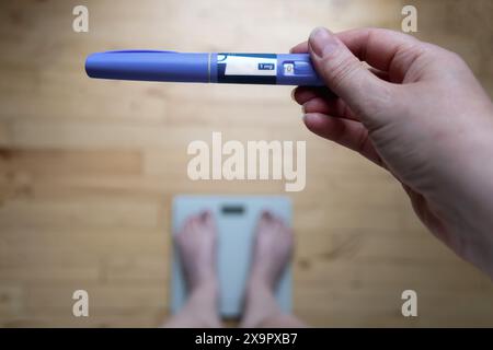 Penna per iniezione di insulina Ozempic per diabetici e perdita di peso. La donna si pesa e tiene Ozempic in mano. Concetto di perdita di peso. Foto Stock