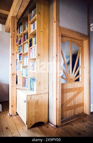 Libreria in legno nel soggiorno in stile rustico vintage, mobili in legno in un cottage, casa di famiglia. Foto Stock