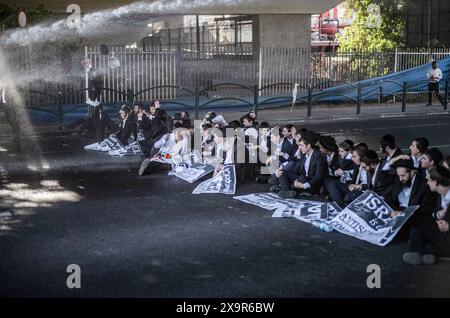 Bnei Brak, Israele. 2 giugno 2024. La polizia israeliana usa il cannone ad acqua per disperdere i manifestanti Ultra-ortodossi che stanno bloccando una strada a Bnei Brak, durante una protesta contro possibili cambiamenti nelle leggi esentano gli uomini Ultra-ortodossi dalla coscrizione militare. Crediti: Ilia Yefimovich/dpa/Alamy Live News Foto Stock