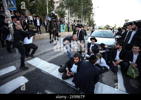 La polizia DI PROTESTA DI DIFESA ISRAELIANA MIDEAST rimuove gli ebrei ultra-ortodossi che bloccano una strada durante una protesta contro la coscrizione militare al di fuori della Corte suprema israeliana a Gerusalemme, 2 giugno 2024. La Corte Suprema d'Israele ascolta il 2 giugno una risposta dello stato sulla questione del reclutamento ultra ortodosso, dopo aver precedentemente prorogato un termine per la presentazione da parte del governo di un piano di coscrizione per gli ebrei ultra-ortodossi, che sono tradizionalmente esenti dal servizio militare. Foto di saeed qaq Copyright: XSAEEDQAQx AX4X2597 Foto Stock