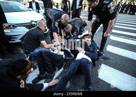 La polizia DI PROTESTA DI DIFESA ISRAELIANA MIDEAST rimuove gli ebrei ultra-ortodossi che bloccano una strada durante una protesta contro la coscrizione militare al di fuori della Corte suprema israeliana a Gerusalemme, 2 giugno 2024. La Corte Suprema d'Israele ascolta il 2 giugno una risposta dello stato sulla questione del reclutamento ultra ortodosso, dopo aver precedentemente prorogato un termine per la presentazione da parte del governo di un piano di coscrizione per gli ebrei ultra-ortodossi, che sono tradizionalmente esenti dal servizio militare. Foto di saeed qaq Copyright: XSAEEDQAQx AX4X2569 Foto Stock