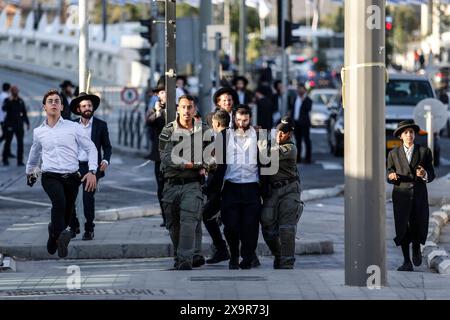 La polizia DI PROTESTA DI DIFESA ISRAELIANA MIDEAST rimuove gli ebrei ultra-ortodossi che bloccano una strada durante una protesta contro la coscrizione militare al di fuori della Corte suprema israeliana a Gerusalemme, 2 giugno 2024. La Corte Suprema d'Israele ascolta il 2 giugno una risposta dello stato sulla questione del reclutamento ultra ortodosso, dopo aver precedentemente prorogato un termine per la presentazione da parte del governo di un piano di coscrizione per gli ebrei ultra-ortodossi, che sono tradizionalmente esenti dal servizio militare. Foto di saeed qaq Copyright: XSAEEDQAQx  B9Z4017 Foto Stock