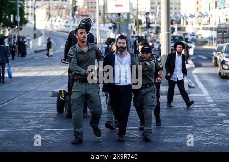 La polizia DI PROTESTA DI DIFESA ISRAELIANA MIDEAST rimuove gli ebrei ultra-ortodossi che bloccano una strada durante una protesta contro la coscrizione militare al di fuori della Corte suprema israeliana a Gerusalemme, 2 giugno 2024. La Corte Suprema d'Israele ascolta il 2 giugno una risposta dello stato sulla questione del reclutamento ultra ortodosso, dopo aver precedentemente prorogato un termine per la presentazione da parte del governo di un piano di coscrizione per gli ebrei ultra-ortodossi, che sono tradizionalmente esenti dal servizio militare. Foto di saeed qaq Copyright: XSAEEDQAQx  B9Z4054 Foto Stock