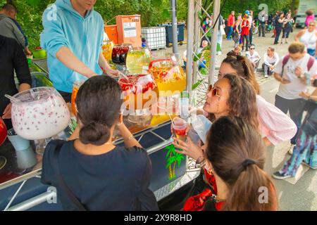 Berlino, Germania. 22. 07. 2023. fila di grandi ciotole di vetro piene di varie bevande colorate. Due persone dietro il bancone. le giovani ragazze attraenti comprano Foto Stock