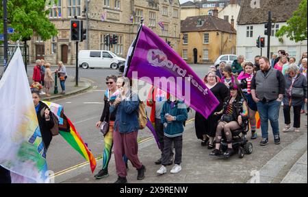 Gruppo di persone a Calne che partecipano a una sfilata di orgoglio con bandiere vibranti su una strada della città Foto Stock