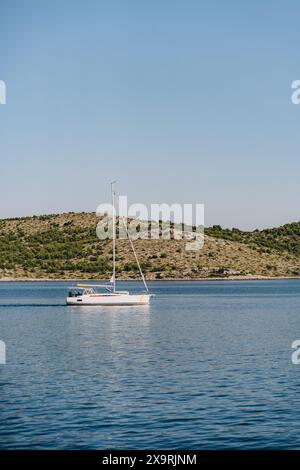 Barca a vela lungo la spiaggia dell'isola di Dugi Otok sotto il cielo blu, fuga nel mare Adriatico, Croazia Foto Stock