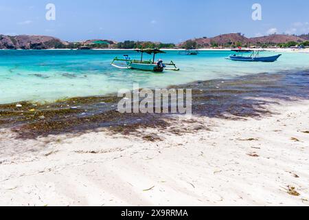 Barca accanto alla plastica galleggiante e alla spazzatura in un caldo oceano tropicale a Tanjung Aan, Lombok, Indonesia Foto Stock