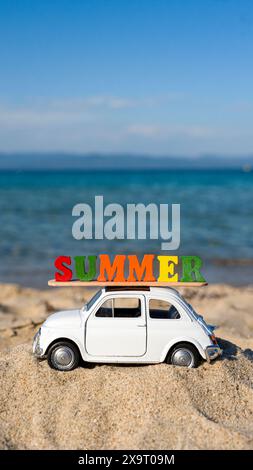 Bella auto con cartello estivo sul tetto sulla spiaggia pronta per le vacanze estive Foto Stock