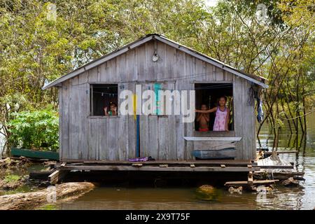 Casa galleggiante, bambini alla finestra, sull'Amazzonia Foto Stock