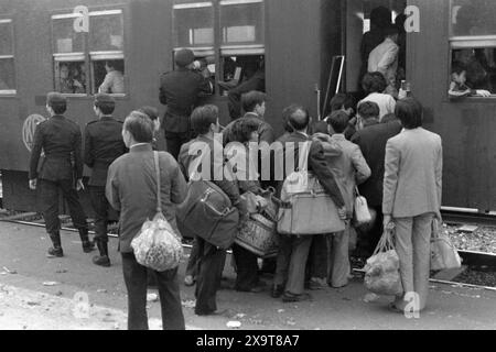 Passeggeri a bordo di un treno diesel diretto a sud, stazione ferroviaria lo Wu, Kowloon-Canton Railway, Hong Kong, Capodanno lunare 1981. La folla è appena tornata a Hong Kong dalla Cina continentale. I poliziotti sulla piattaforma sono impegnati nella gestione della folla, a causa dell'elevato numero di passeggeri durante le festività. Questo era prima che il KCR fosse elettrificato nei primi anni '1980 Foto Stock