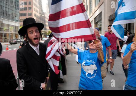 I membri di Neturei Karta, di sinistra, che sono ebrei ultra-ortodossi e anti-sionisti, protestano per strada vicino ai sostenitori di Israele, di destra, durante la 59a annuale parata della giornata d'Israele. La Israel Day Parade, che commemora la cultura ebraica, attira rivelatori, carri allegorici e organizzazioni israeliane-americane nel centro di Manhattan, New York. La parata si svolse quasi otto mesi dopo l'inizio della guerra Israele-Hamas. La parata di quest'anno si è concentrata sulla solidarietà israeliana nella guerra in corso. Il dipartimento di polizia di New York aumentò la sicurezza per la parata a causa delle preoccupazioni delle proteste pro-palestinesi. Foto Stock