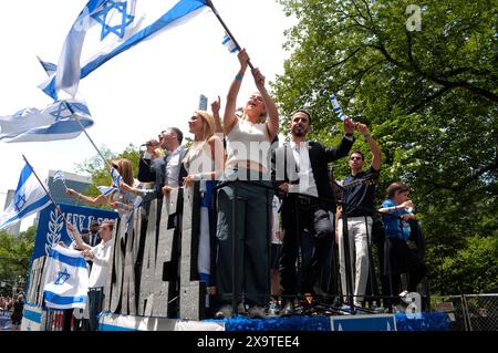 I partecipanti alla sfilata sventolano le bandiere israeliane mentre si trovano su un galleggiante sulla Fifth Avenue alla 59a edizione della Israel Day Parade. La Israel Day Parade, che commemora la cultura ebraica, attira rivelatori, carri allegorici e organizzazioni israeliane-americane nel centro di Manhattan, New York. La parata si svolse quasi otto mesi dopo l'inizio della guerra Israele-Hamas. La parata di quest'anno si è concentrata sulla solidarietà israeliana nella guerra in corso. Il dipartimento di polizia di New York aumentò la sicurezza per la parata a causa delle preoccupazioni delle proteste pro-palestinesi. Foto Stock