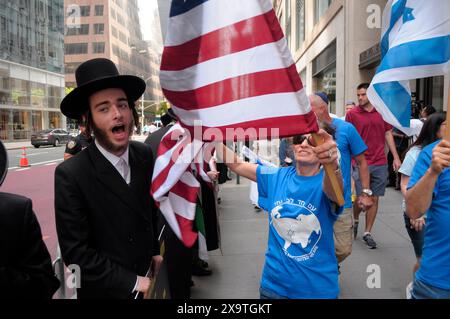 I membri di Neturei Karta, di sinistra, che sono ebrei ultra-ortodossi e anti-sionisti, protestano per strada vicino ai sostenitori di Israele, di destra, durante la 59a annuale parata della giornata d'Israele. La Israel Day Parade, che commemora la cultura ebraica, attira rivelatori, carri allegorici e organizzazioni israeliane-americane nel centro di Manhattan, New York. La parata si svolse quasi otto mesi dopo l'inizio della guerra Israele-Hamas. La parata di quest'anno si è concentrata sulla solidarietà israeliana nella guerra in corso. Il dipartimento di polizia di New York aumentò la sicurezza per la parata a causa delle preoccupazioni delle proteste pro-palestinesi. (Foto di Jimin Ki Foto Stock