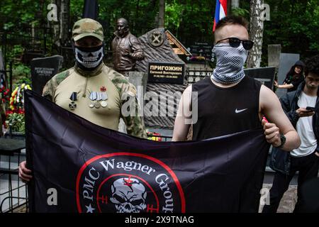 I combattenti del gruppo militare privato "Wagner" si trovano vicino alla scultura del capo dei mercenari russi Yevgeny Prigozhin, installata sulla sua tomba, durante la celebrazione del suo compleanno al cimitero Porokhovskoye di San Pietroburgo. Un monumento al fondatore del Wagner PMC, Evgeniy Prigozhin, è stato inaugurato nel cimitero Pokhorovskoye di San Pietroburgo. Il 1° giugno avrebbe compiuto 63 anni. I membri del PMC e i civili posero fiori al monumento. Evgeny Prigozhin morì il 23 agosto 2023, a causa dello schianto del suo jet d'affari Embraer nella regione di Tver in Russia. (Foto b Foto Stock