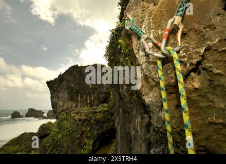 Ganci imbullonati con guide e una fune installati come sistema di ancoraggio per una sessione di arrampicata sportiva sulla superficie di una collina calcarea. Foto Stock