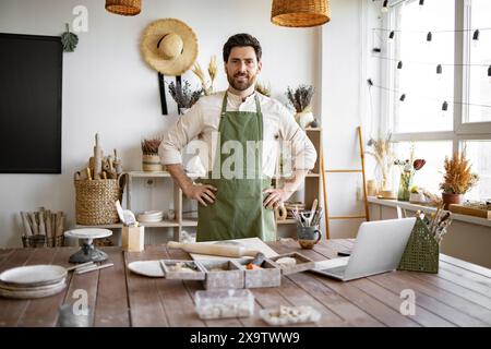 Ritratto del vasaio maschile, in piedi di fronte al tavolo con gli attrezzi per la scultura. Foto Stock