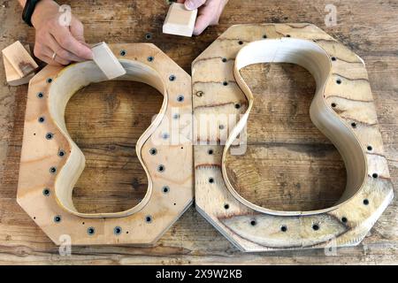 PRODUZIONE - 27 maggio 2024, Sassonia, Lipsia: Nel suo piccolo laboratorio ad ovest di Lipsia, il chitarrista addestrato Tom Ziegenspeck attacca il collo e i blocchi terminali a due corpi di ukulele realizzati in abete alpino bavarese. Il maestro di 31 anni che produce l'ukulele, particolarmente popolare nelle Hawaii, da 10 anni, è l'unico produttore di ukulele in Germania a costruire un ukulele per gli amanti della musica con quattro lati di basso aggiuntivi invece dei soliti quattro. Suonato elettricamente, il suo esotico suono hawaiano è particolarmente popolare nei gruppi musicali, ma anche nelle Hawaii. Il Foto Stock