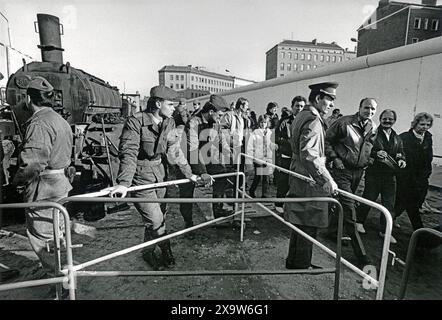 Maueröffnung an der Bernauer Strasse, Berlino, DDR, 11. Novembre 1989 DDR, Berlino, 11.11.1989, Eröffnung des Grenzübergangs Bernauer Strasse, Berliner Mauer, Grenzstreifen, Blick in Richtung DDR, DDR Grenzsoldaten stehen verlegen an der frisch geöffneten Mauerstelle, ratlos, DDR Bürger strömen erstmals ungehindert in den Westen, nach Westberlin, Reisefreiheit, Die Mauer ist erstmals erstmals nach, Joffen, 38 Joffren nach, Joffen, Joffen frisch geräumter und planierter ehemaliger Todesstreifen, Teermaschine, zwei Tage nach dem historischen Mauerfall, Maueröffnung, Grenzöffnung auf Höhe der Kreuzung Bernauer Straße/Schwedter Str Foto Stock