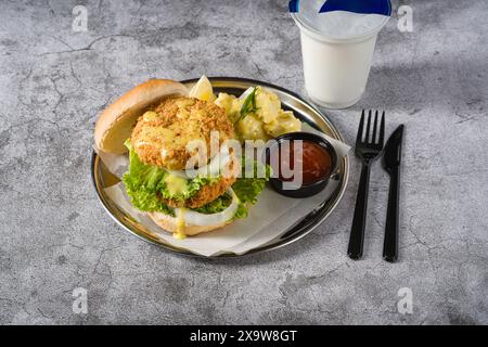 Doppio hamburger di pesce con insalata di patate su un piatto di metallo Foto Stock