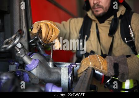 Vigile del fuoco in uniforme con equipaggiamento per motori antincendio in stazione, fuoco selettivo Foto Stock